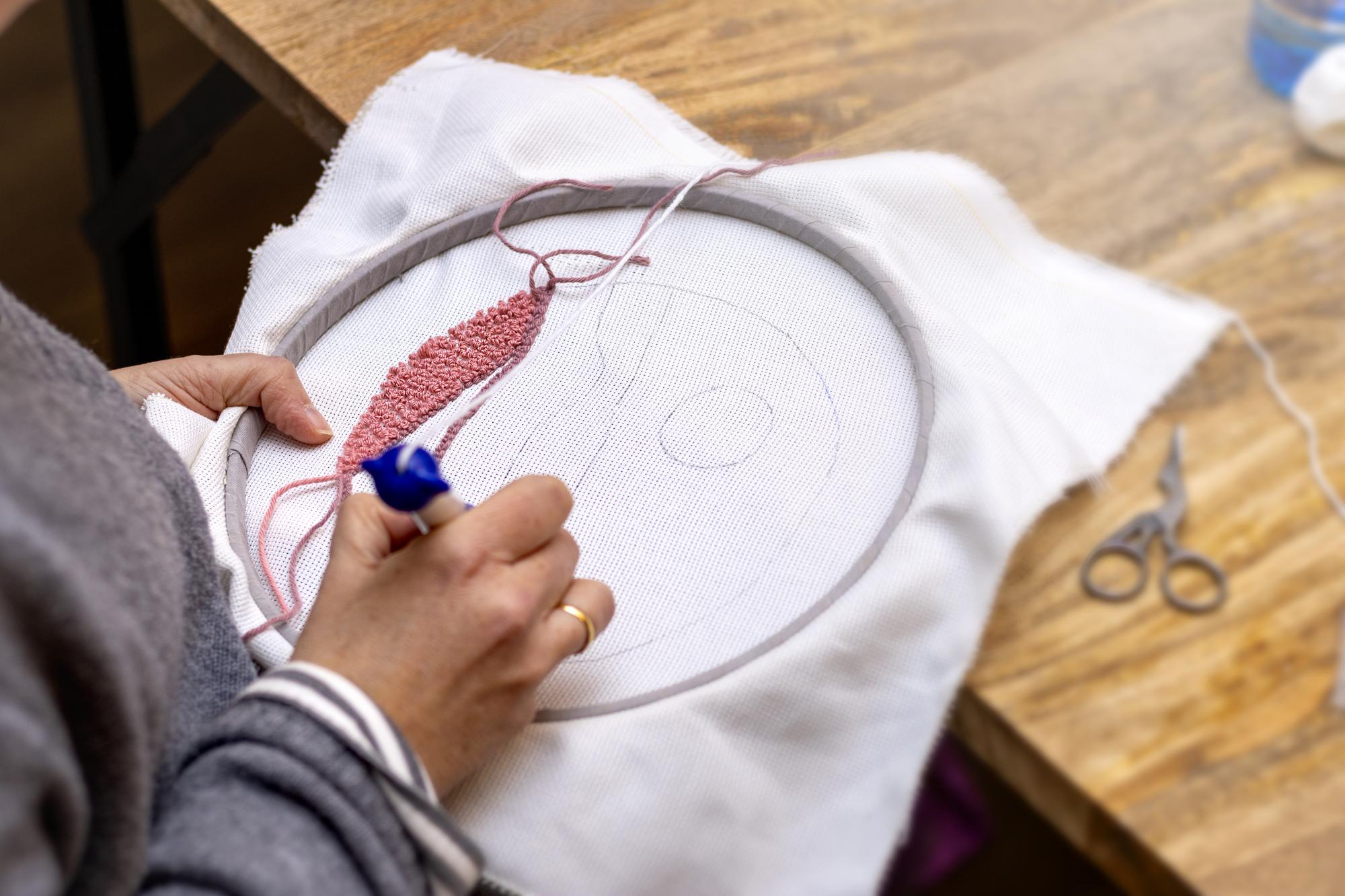 Artisan hands working on embroidery hoop in studio